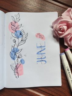 an open notebook with the word love written on it next to some markers and a rose