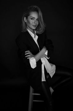 black and white photograph of a woman leaning on a bar stool with her arms crossed