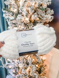 someone holding up a chunk yarn in front of a christmas tree