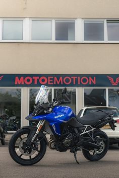 a blue motorcycle parked in front of a motormoton store with cars behind it