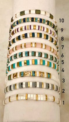 a stack of bracelets sitting on top of a white table next to a ruler