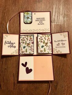 four cards with hearts and flowers on them sitting on top of a wooden table next to each other