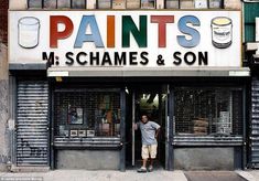 a man standing in the doorway of a paint shop