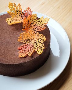 a chocolate cake on a white plate with orange and yellow decorations in the top layer