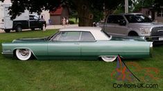 an old green car is parked in the grass