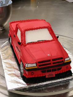 a cake shaped like a red car on top of a silver platter with white frosting