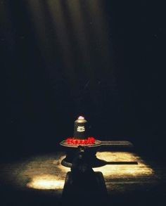 a black table topped with a cake covered in strawberries and a light shining down on it