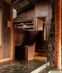 a stone floor and wooden walls in a room with steps leading to the second floor