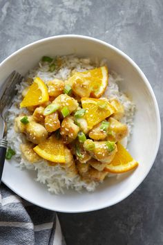 a white bowl filled with rice and oranges on top of a gray tablecloth