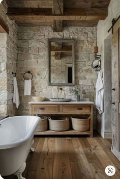 an old fashioned bathroom with stone walls and wood flooring, including a claw foot bathtub