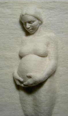 a sculpture of a woman holding a baby in it's arms, on top of a white surface