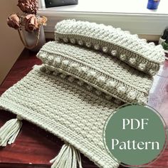 three crocheted pillows sitting on top of a wooden table next to a window