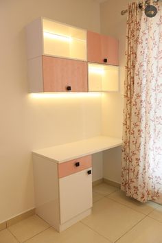 a white desk sitting under a window next to a wall mounted shelf with lights on it