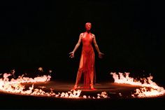 a woman in red dress standing on fire