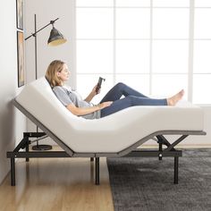 a woman is sitting in a white reclining chair holding a remote control and watching tv