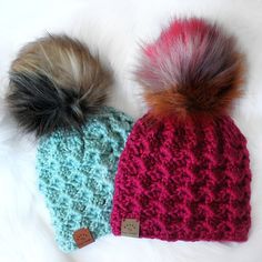 two knitted hats with fur pom - poms on top of each other