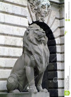 a statue of a lion on the side of a building with an arch in the background