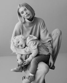 a woman sitting on top of a chair holding a baby