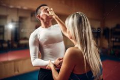 a man standing next to a woman in a gym with his hand on her face