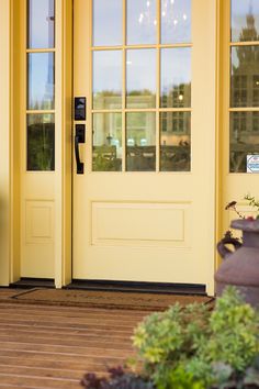 the front door to a yellow building with two telephones on it's side