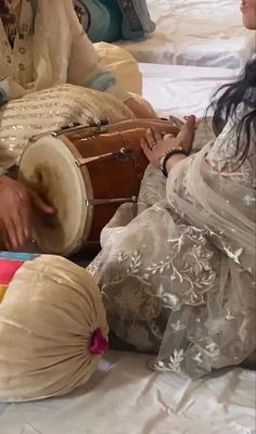 two people sitting on a bed playing with musical instruments in the middle of the day