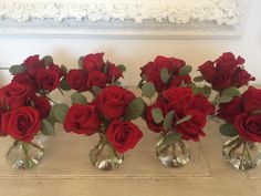 five vases with red roses in them on a table