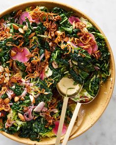 a bowl filled with greens, radishes and other toppings next to a wooden spoon