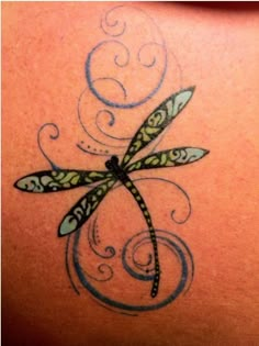 a dragonfly tattoo on the back of a woman's shoulder