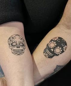 two people with matching tattoos on their arms, one has a skull and the other has a flower