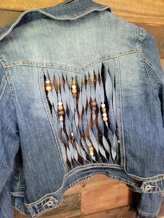 the back of a jean jacket with feathers on it