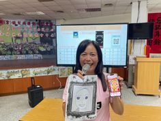 a woman is holding up an item in front of her face and smiling at the camera