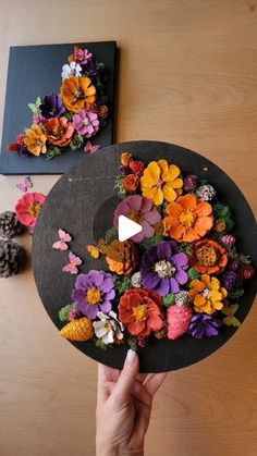 a person is holding a black hat with flowers on it and the video has been taken from above