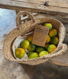 a basket full of lemons sitting on top of a wooden bench next to a sign