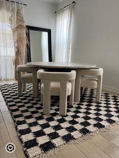 a black and white checkered area rug with four chairs around a round dining table