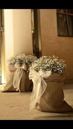 two vases with baby's breath flowers in them sitting on the floor next to a door