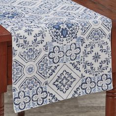 a blue and white table runner on top of a wooden table