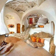 a living room with white walls and stone steps leading up to the second floor area