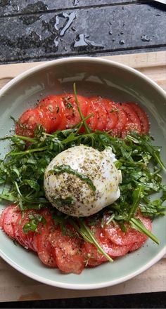 a white bowl filled with lots of food on top of a wooden table