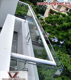 glass railing on the side of a building with trees in the background