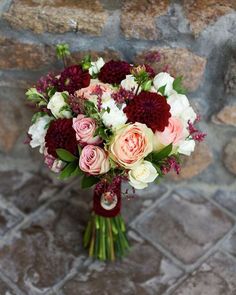 a bouquet of flowers sitting on top of a stone floor next to a brick wall