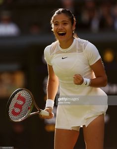 a female tennis player is laughing and holding her racquet