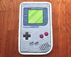 an old nintendo game boy towel is laying on the floor next to a wooden floor