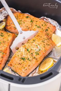 two salmons being cooked in an air fryer with lemon slices and parsley