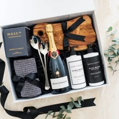 an open box containing bottles of wine, spoons and other personal care items on a table