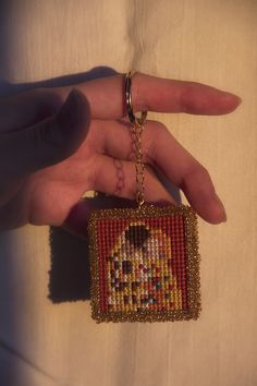 a hand is holding a beaded square keychain