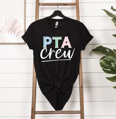 a black t - shirt with the words pta crew printed on it sitting next to a ladder