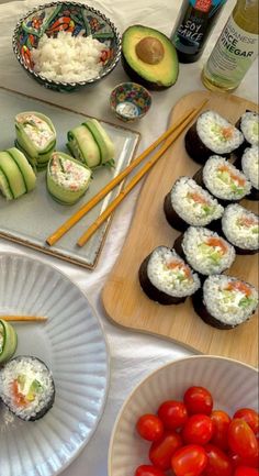 sushi and avocado are on plates with chopsticks next to them