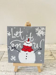 an easel with a snowman painted on it and the words let it snow