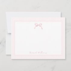 a white card with pink ribbon on it