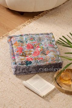 an open book sitting on top of a rug next to a vase and candle holder